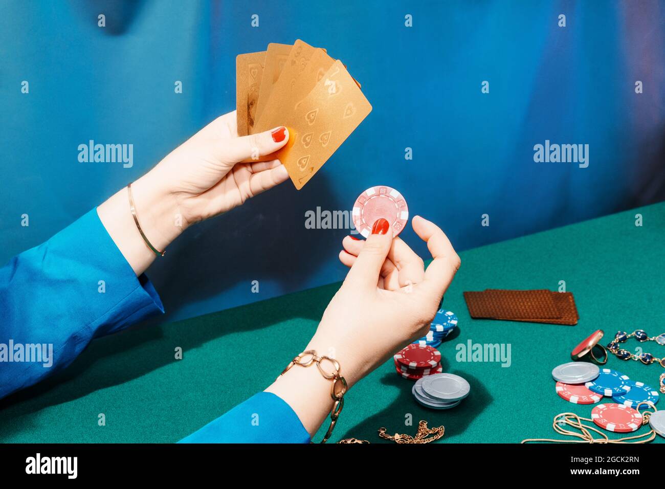 Rognez une femelle méconnaissable avec des cartes et des jetons jouant au poker tout en étant assis à la table verte Banque D'Images