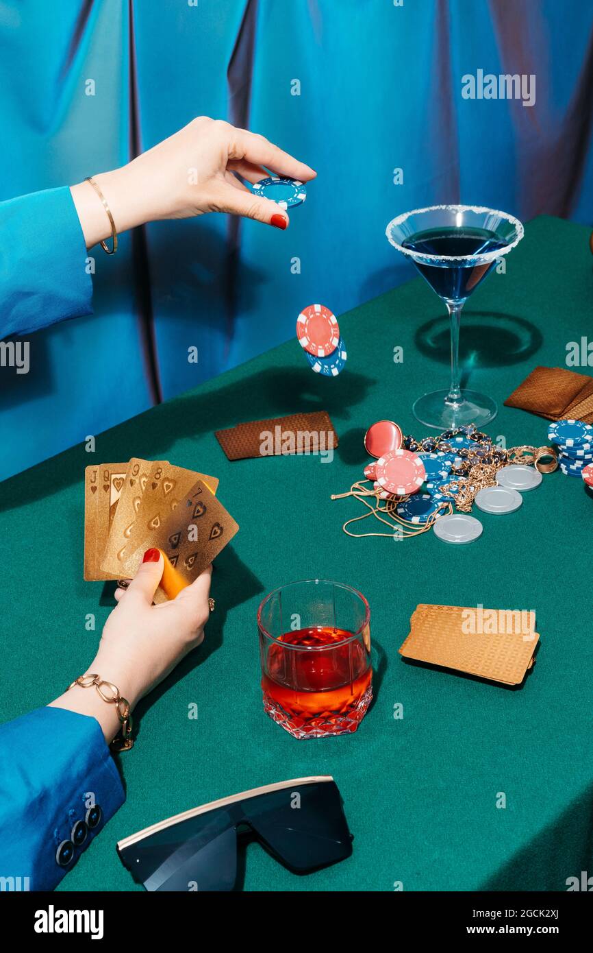 Rognez une femelle méconnaissable avec des cartes et des jetons jouant au poker tout en étant assis à la table verte Banque D'Images