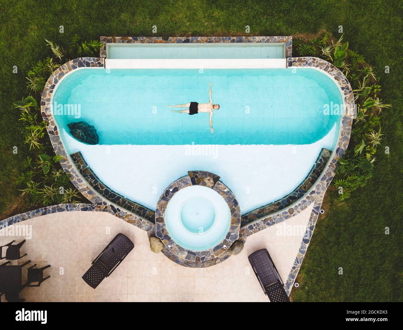 Vue de dessus homme seul dans une piscine profitant d'une journée ensoleillée d'été Banque D'Images