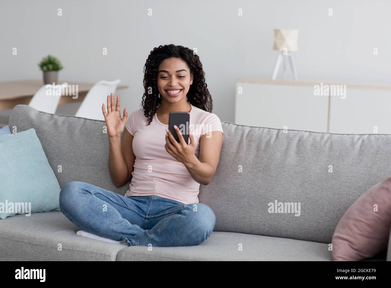 Les appels vidéo, les réseaux sociaux, la sécurité et les appareils modernes à la maison. Souriant millénaire jolie femme noire appelant en ligne, ont la réunion virtuelle, agitant h Banque D'Images