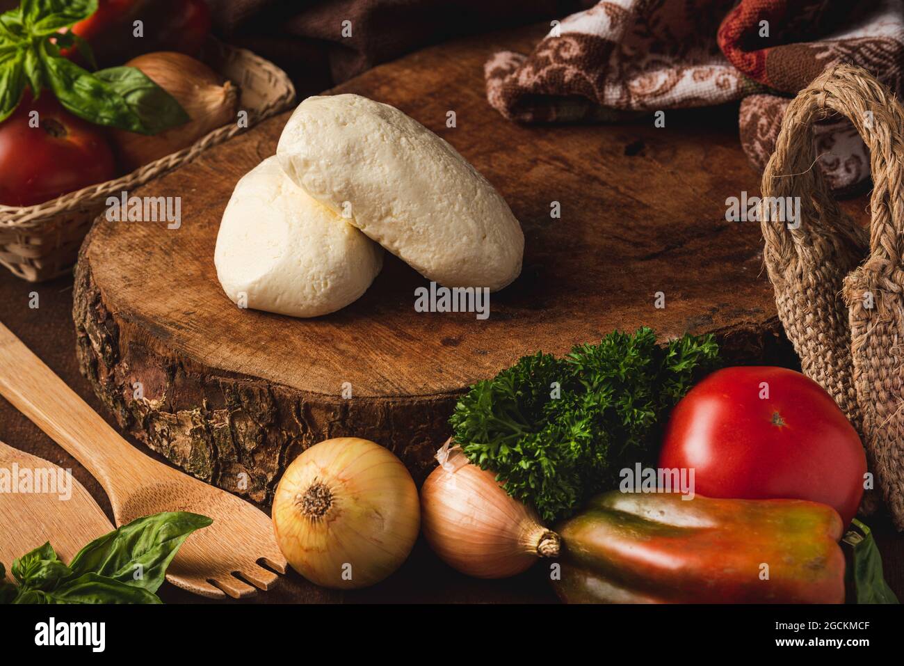 Boules de mozzarella parmi divers produits sains et spatules organiques avec feuilles de basilic sur la table Banque D'Images