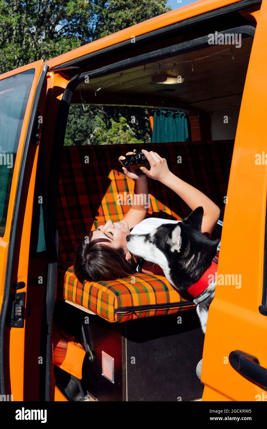 Vue latérale d'une femme voyageur allongé dans un minibus et regardant à travers les photos prises avec un appareil photo pendant les vacances d'été Banque D'Images