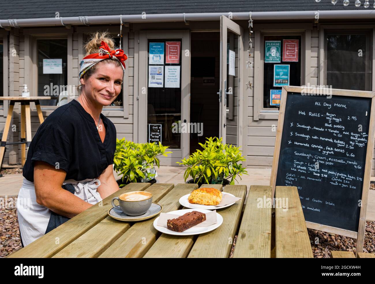Propriétaire du café Rosearista Dannine Stenhouse avec café latte & scone et gâteaux au brownie, East Lothian, Écosse, Royaume-Uni Banque D'Images