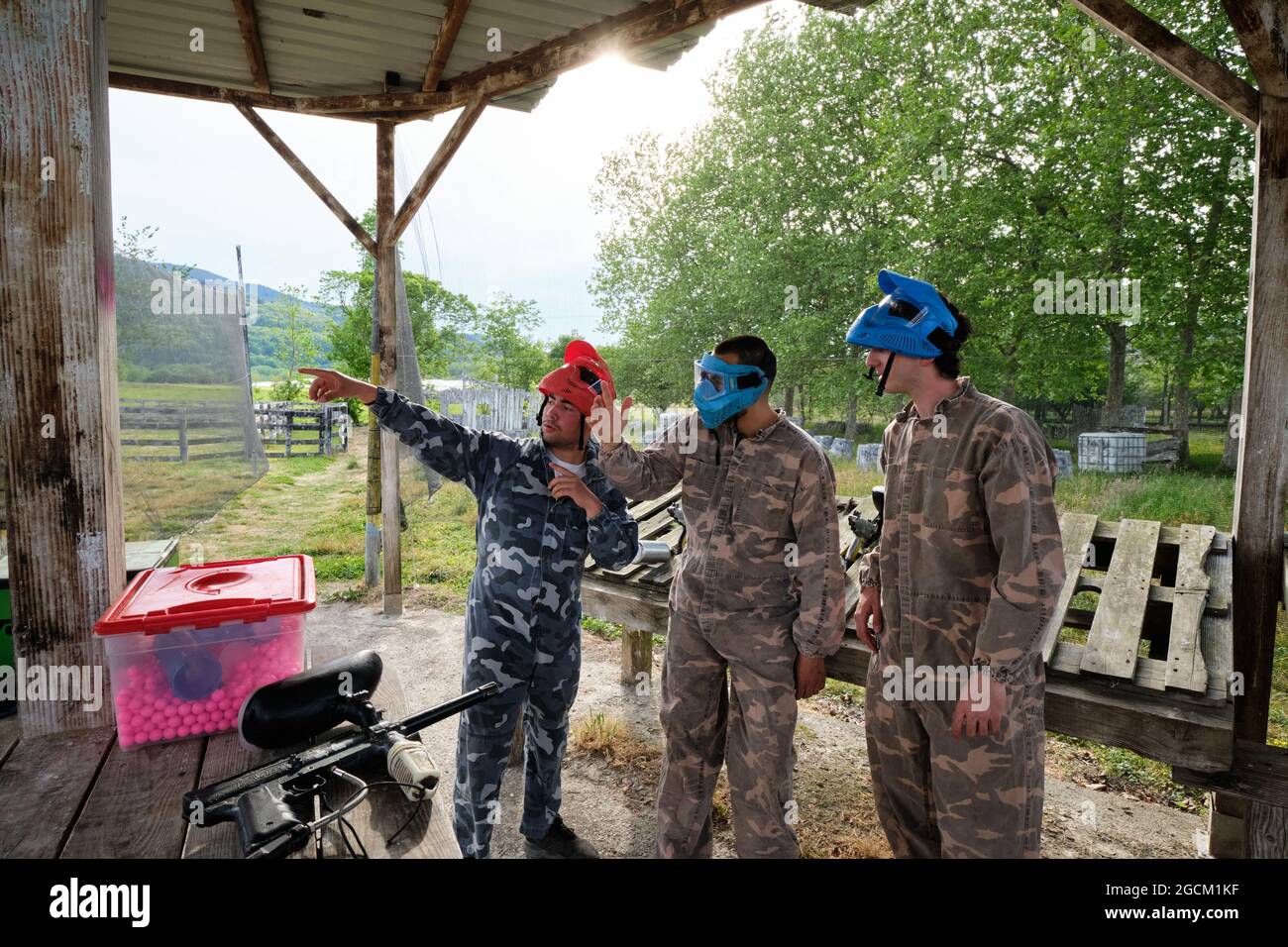 Compagnie de joueurs masculins dans des masques et des vêtements de camouflage se préparant pour jouer au paintball Banque D'Images