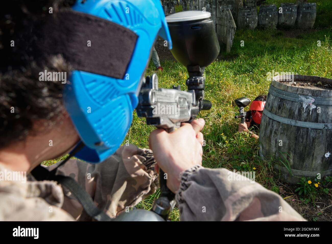 Joueurs de l'équipe méconnaissables en tenue de camouflage et avec des fusils qui se visent les uns les autres tout en jouant au paintball Banque D'Images