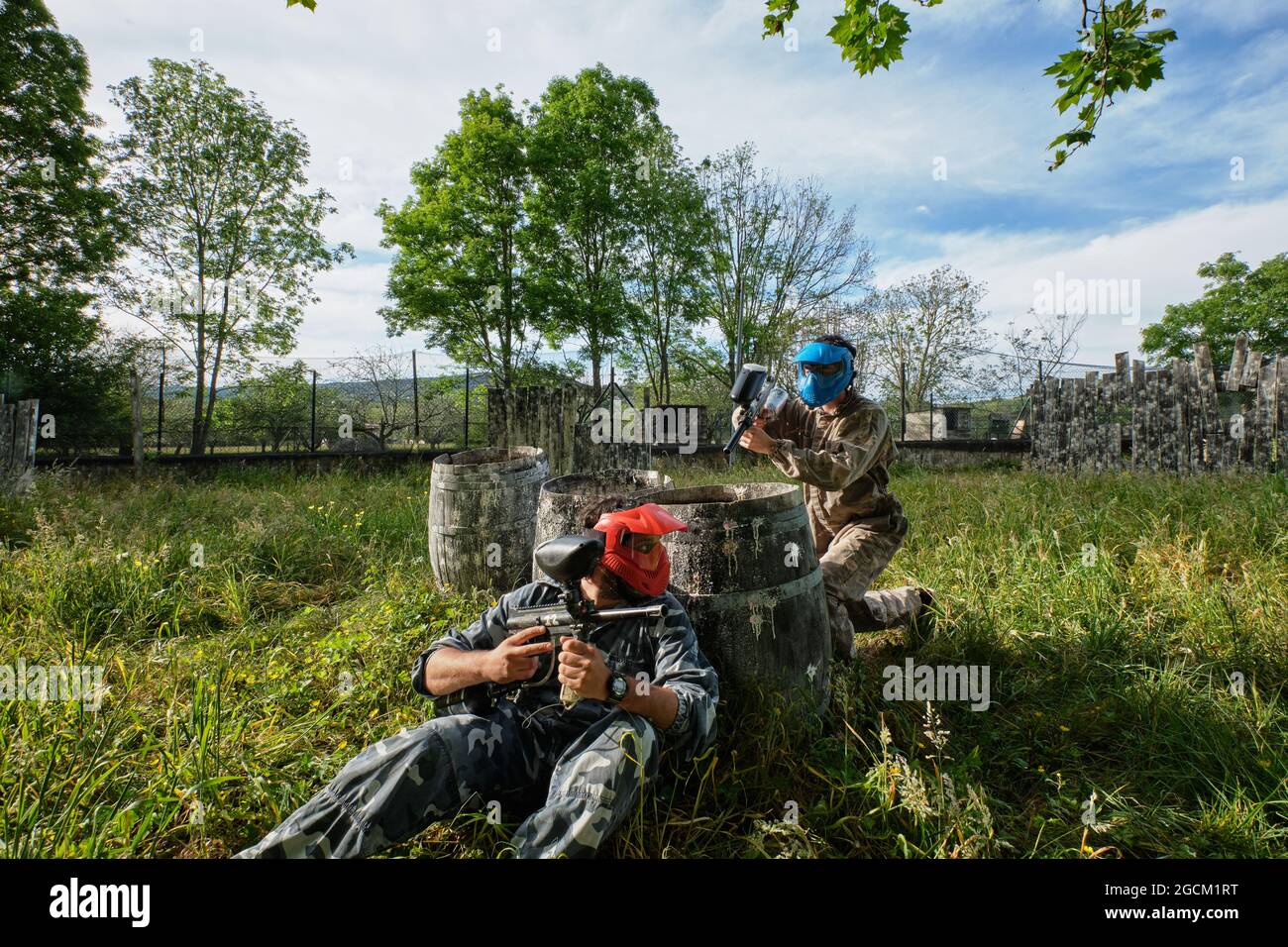 Joueurs de l'équipe méconnaissables en tenue de camouflage et avec des fusils qui se visent les uns les autres tout en jouant au paintball Banque D'Images
