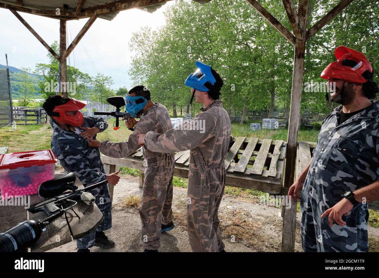 Les joueurs masculins positifs en tenue de camouflage s'amusent avant de jouer au paintball en campagne Banque D'Images