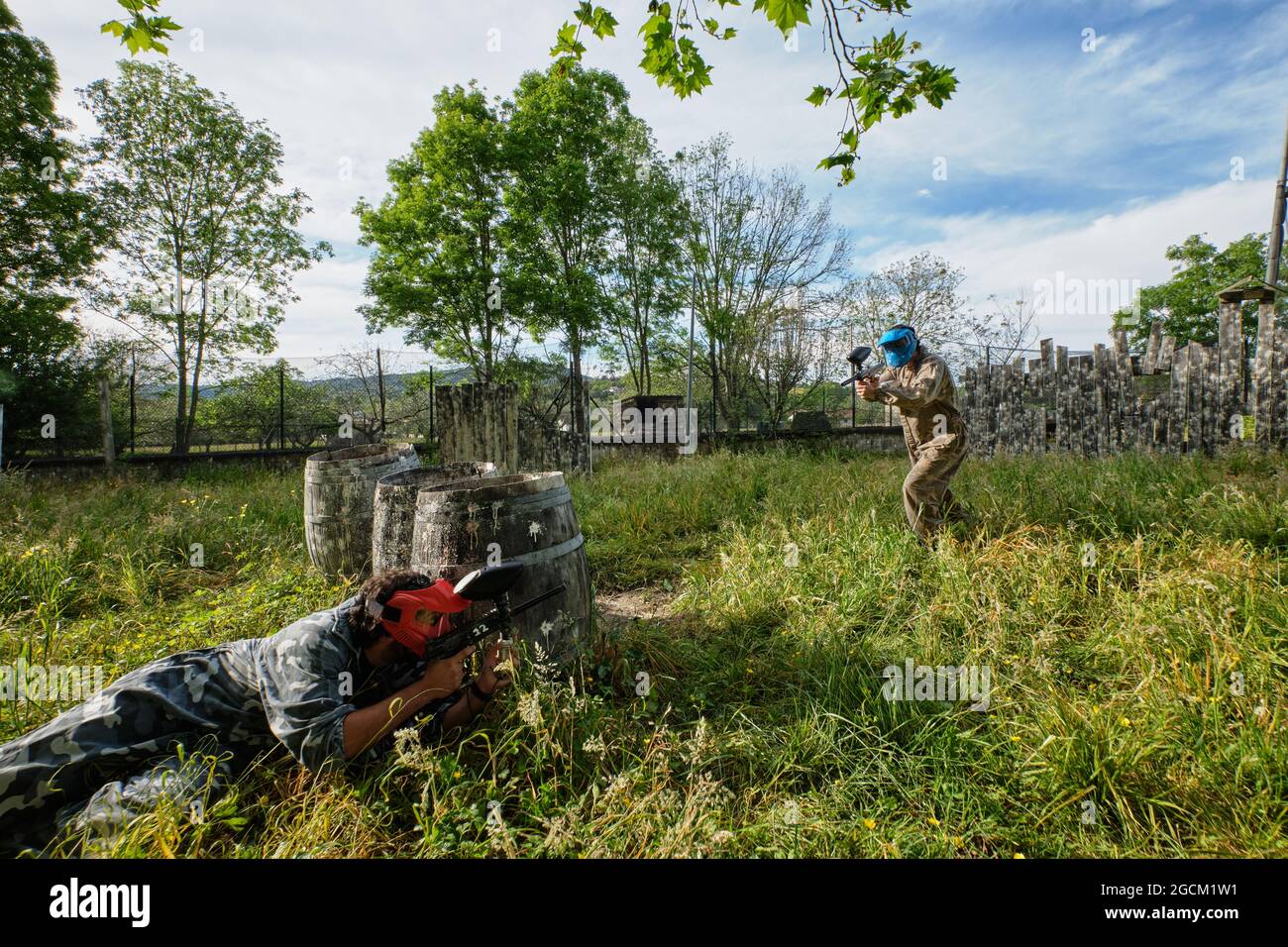 Joueurs de l'équipe méconnaissables en tenue de camouflage et avec des fusils qui se visent les uns les autres tout en jouant au paintball Banque D'Images