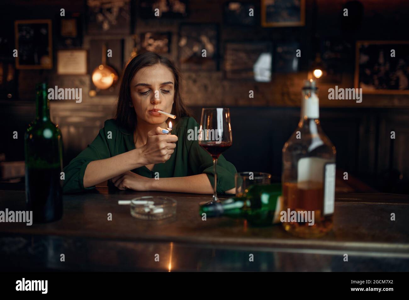 Une femme ivre fume une cigarette au comptoir du bar Banque D'Images