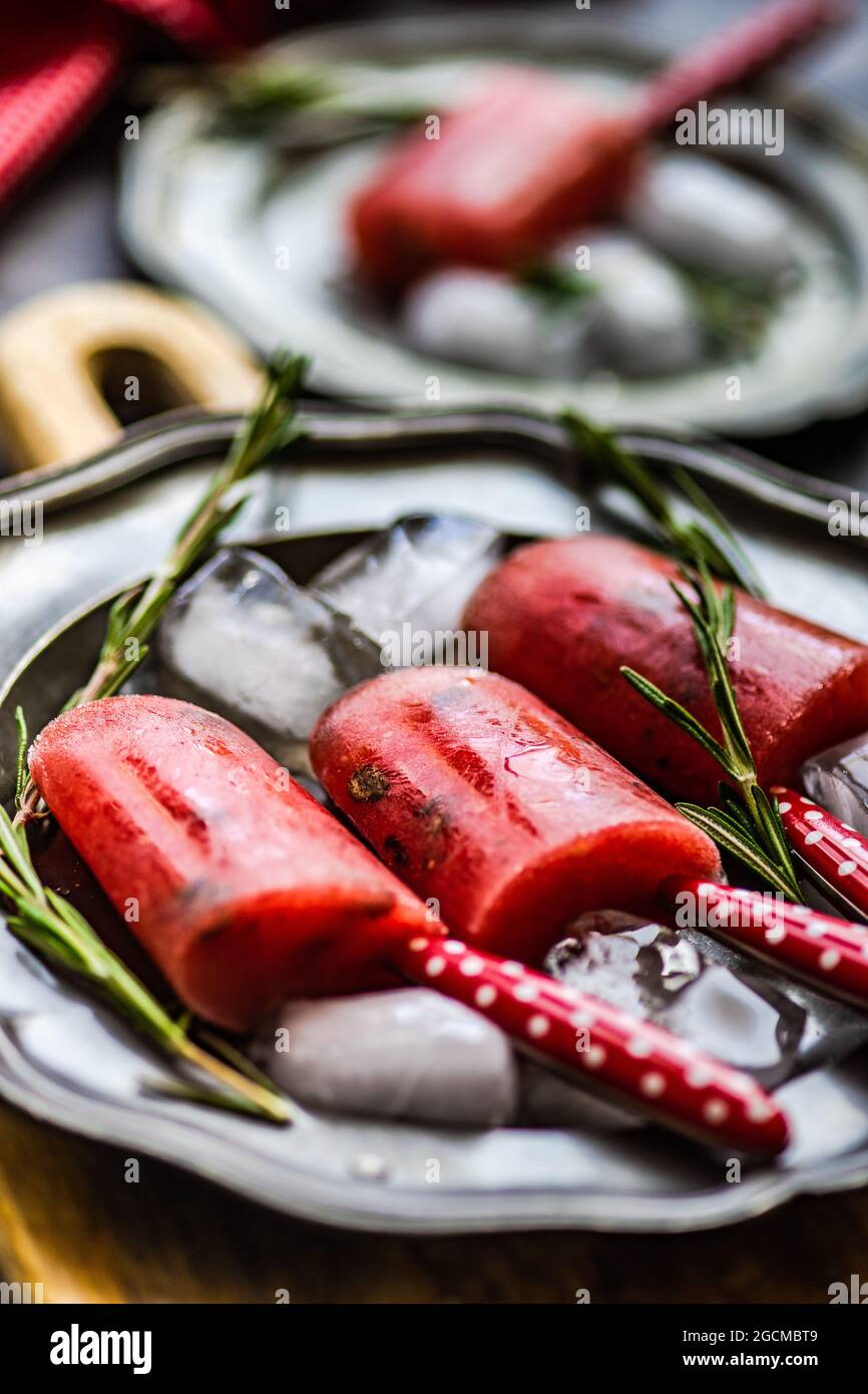Pastèques de pastèque sur une assiette avec des glaçons et du romarin Banque D'Images