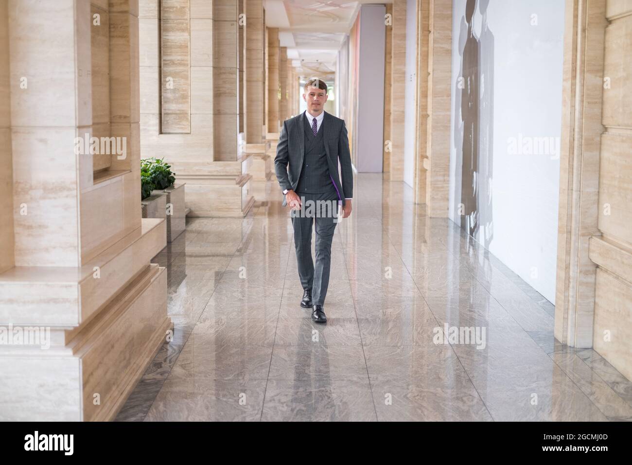 Homme d'affaires vêtu d'un costume gris et marchant près d'un bureau. Photo de haute qualité Banque D'Images