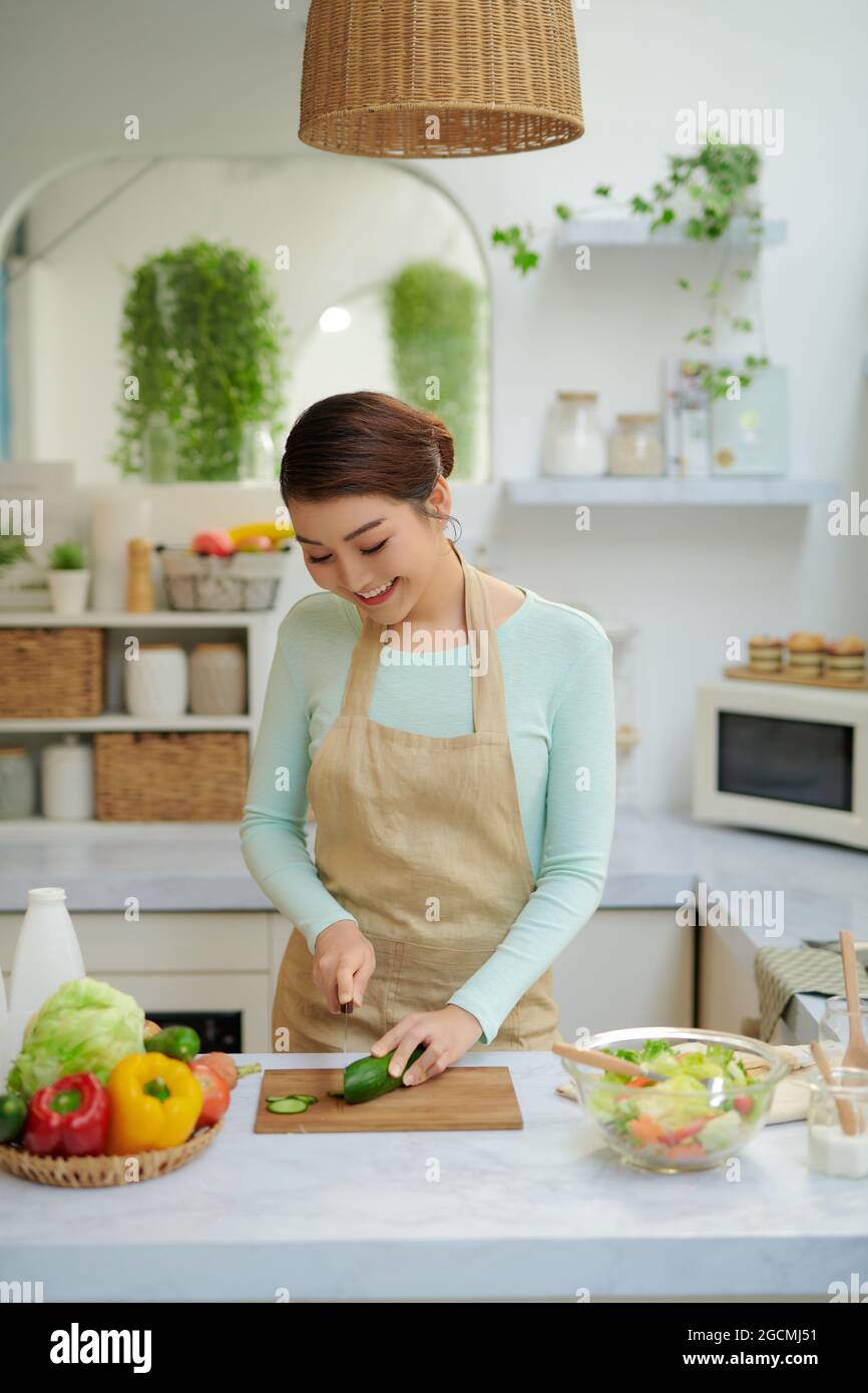 Femme coupant du concombre frais à table, Banque D'Images