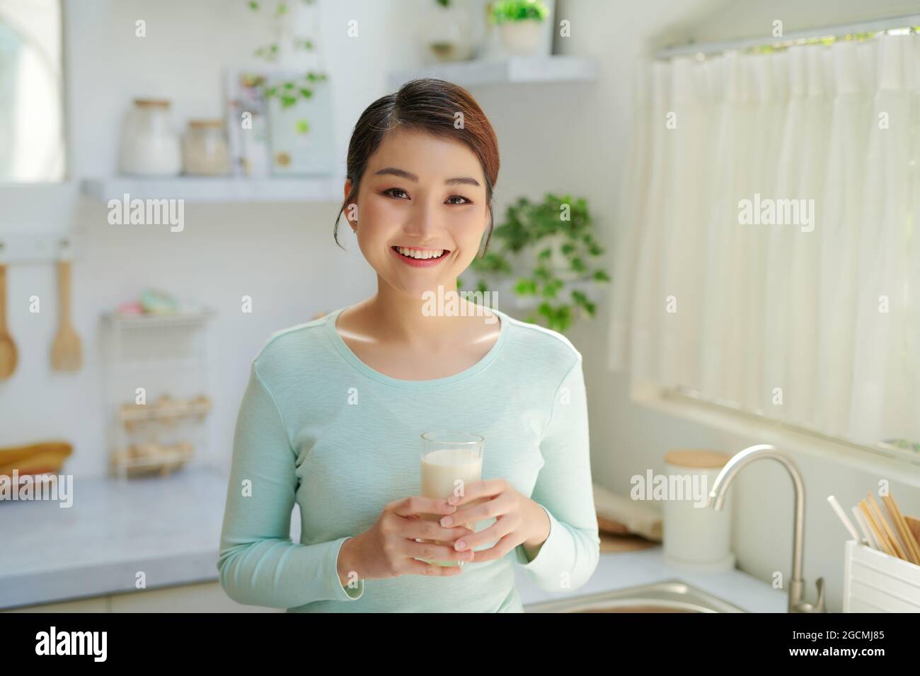 une femme asiatique boit du lait dans la cuisine Banque D'Images