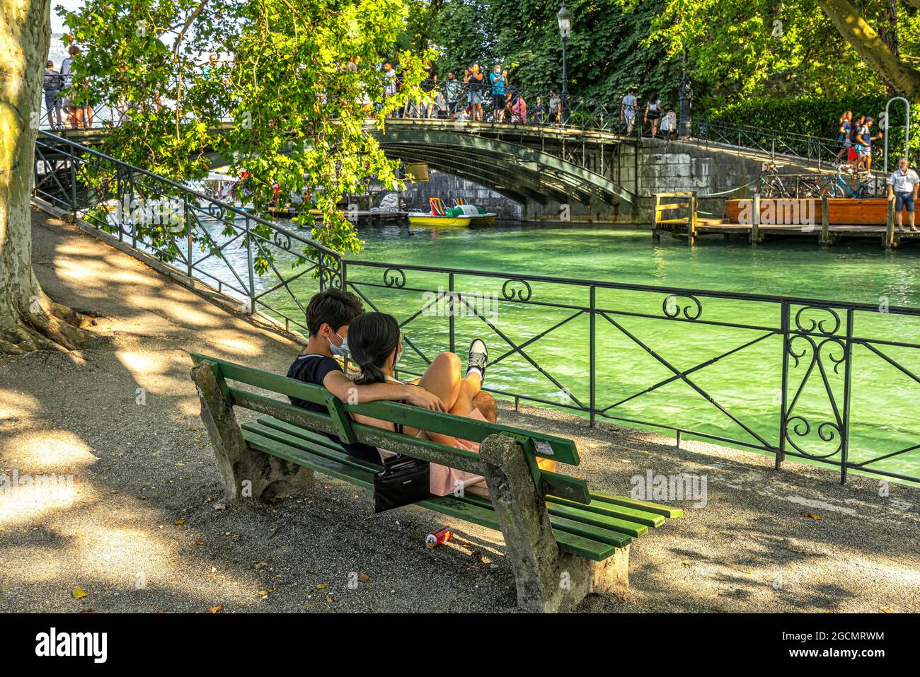Deux amoureux en face du pont des amoureux d'Annecy observent le passage des touristes lors d'une journée d'été. Annecy, département Savoie, France Banque D'Images