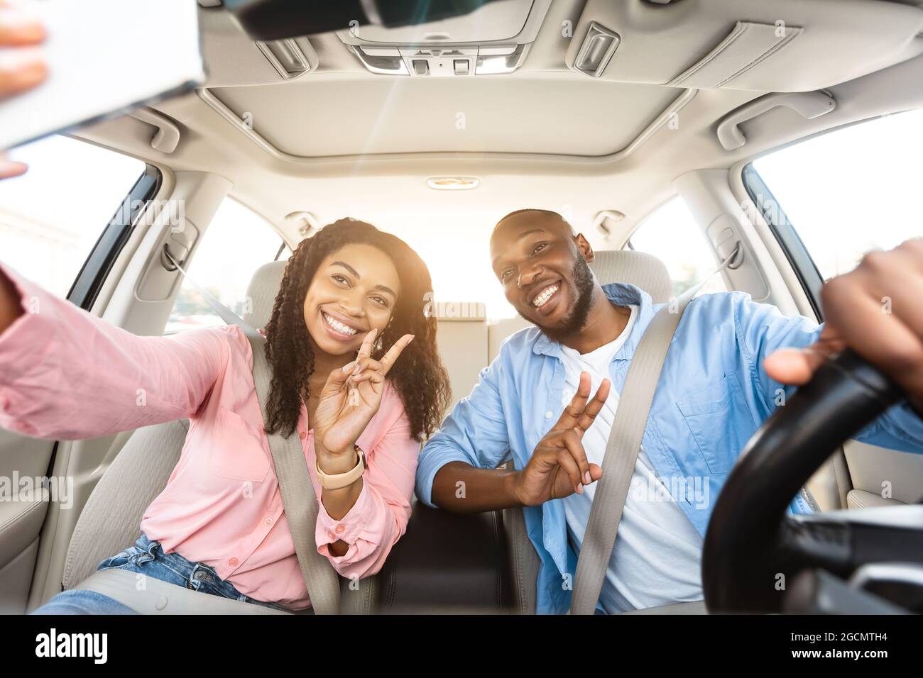 Heureux couple noir conduisant la voiture et prenant le selfie Banque D'Images