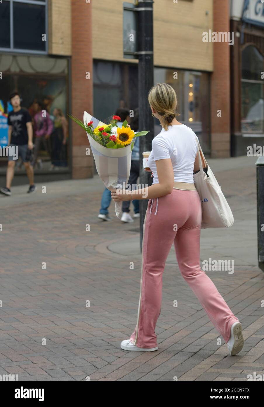Jeune femme avec fleurs, haut blanc et pantalon rose Photo Stock - Alamy