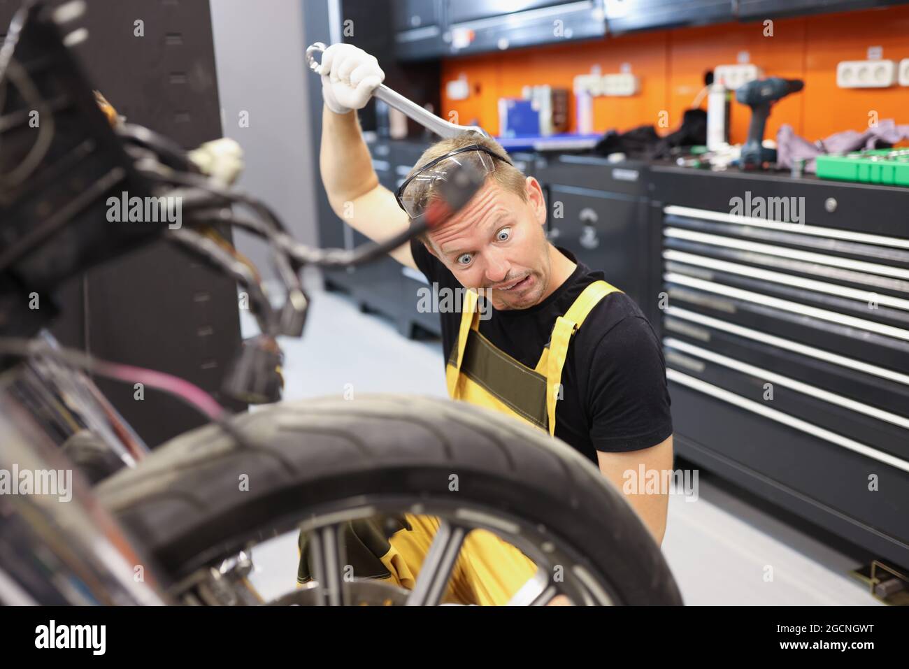 Apprenti-stagiaire pensif, le serrurier pense à la réparation de la moto Banque D'Images