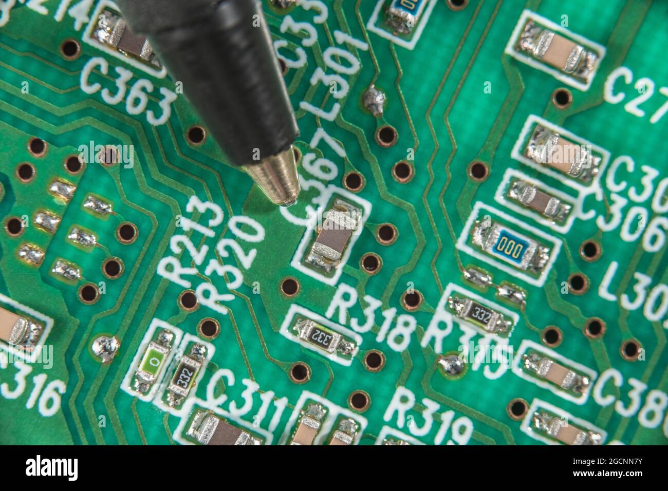 Macro-photo de la carte de circuit imprimé à montage en surface (CMS) montrant les résistances, les condensateurs et le câblage de liaison, le circuit en gros plan. La pointe du stylo à bille donne de la balance. Banque D'Images