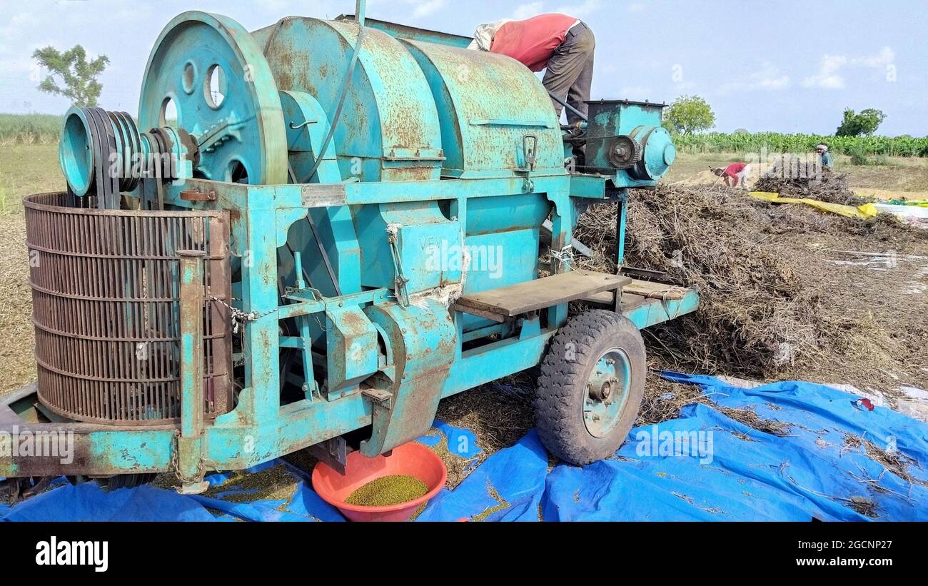 Machine de battage de paddy sur le champ agricole derrière la pile Hey Banque D'Images