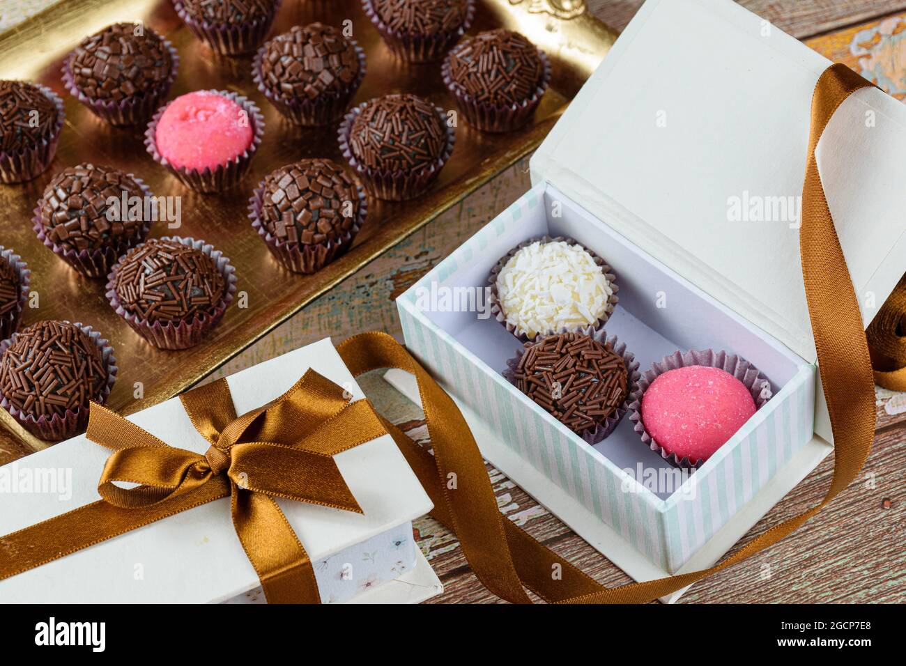 Petite boîte avec trois types de brigadeiros à côté d'un ruban et une boîte avec brigadeiro traditionnel. Banque D'Images