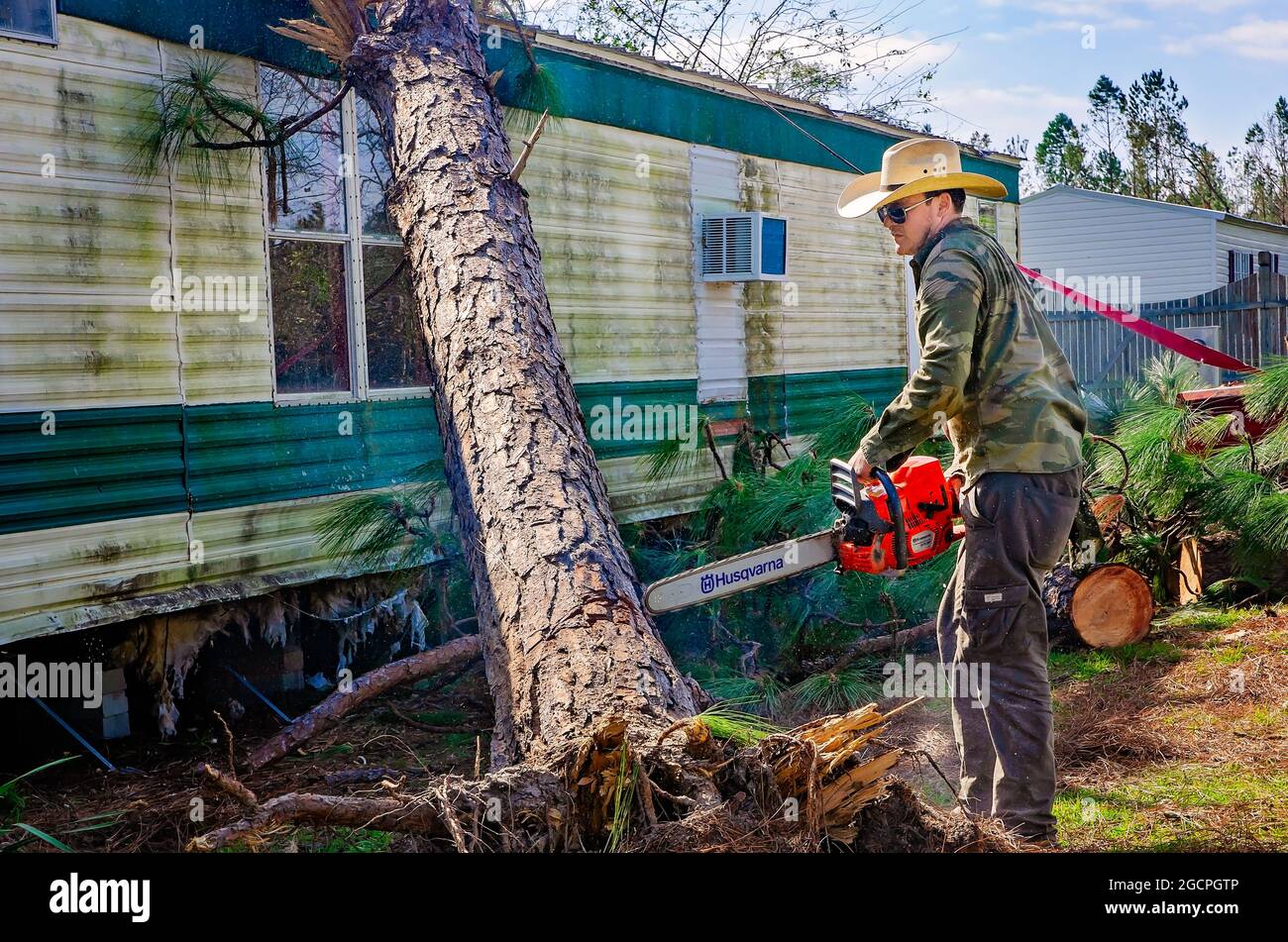 Un homme retire les arbres d'une maison mobile dans le parc de la maison mobile Twin Oaks après l'ouragan Michael, 18 octobre 2018, à Marianna, Floride. Banque D'Images