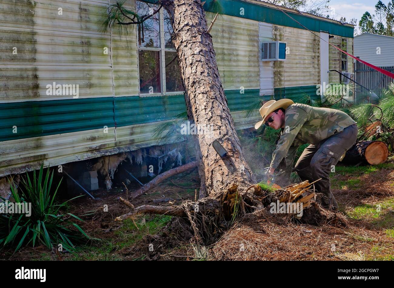 Un homme retire les arbres d'une maison mobile dans le parc de la maison mobile Twin Oaks après l'ouragan Michael, 18 octobre 2018, à Marianna, Floride. Banque D'Images