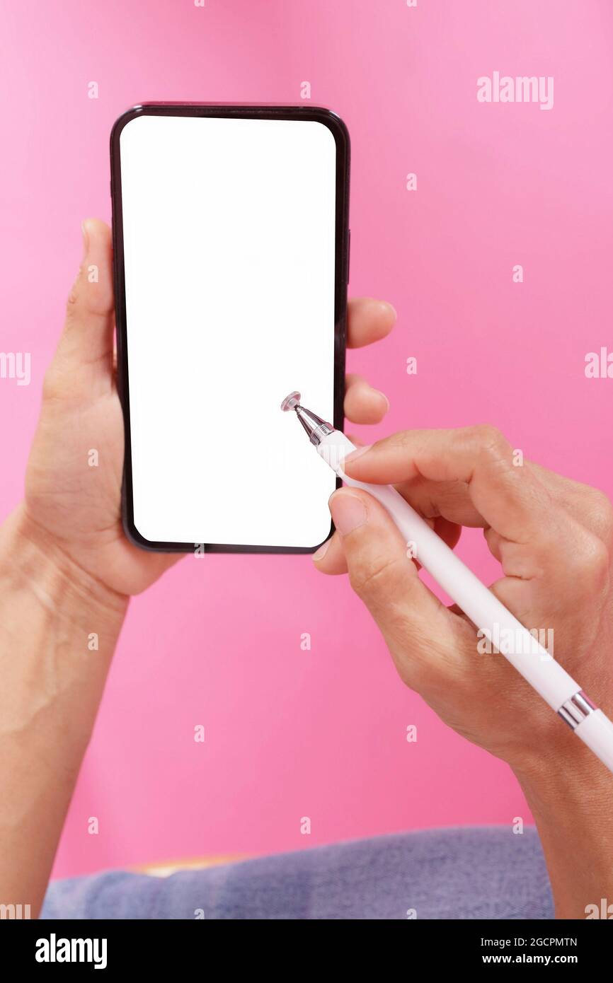 main tenant le téléphone avec un stylo pour un smartphone.sur la scène rose isoler.espace vide pour le texte Banque D'Images