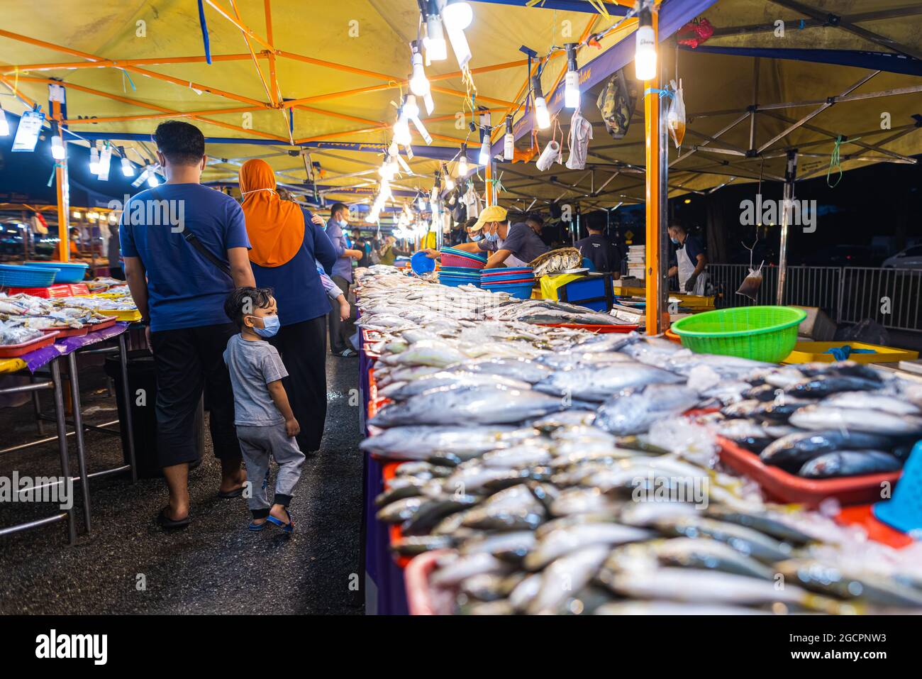 Marché nocturne de la cuisine de rue à Putrajaya, près de Kuala Lumpur. Comptoir de fruits de mer avec poisson frais sur le comptoir. Famille malaise avec un petit garçon passant Banque D'Images