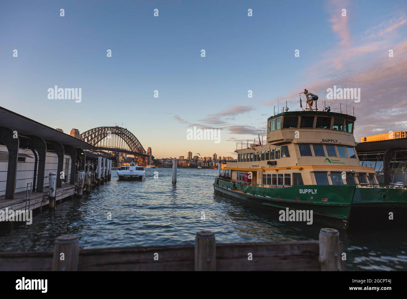 Sydney, Australie - 14 octobre 2020 : les ferries jaunes verts à Circular Quay, Sydney Australie. En arrière-plan, l'immense Harbour Bridge. Coucher de soleil à Banque D'Images