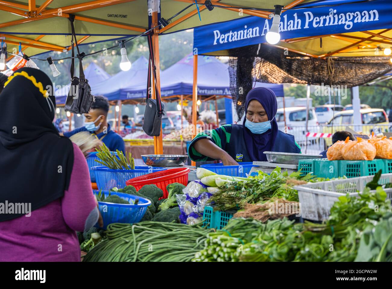 Marchands de légumes sur un marché frais à Putrajaya, près de la capitale Kuala Lumpur. La femme islamique avec hijab vend des légumes. En raison de Covid-19 elle porte f Banque D'Images