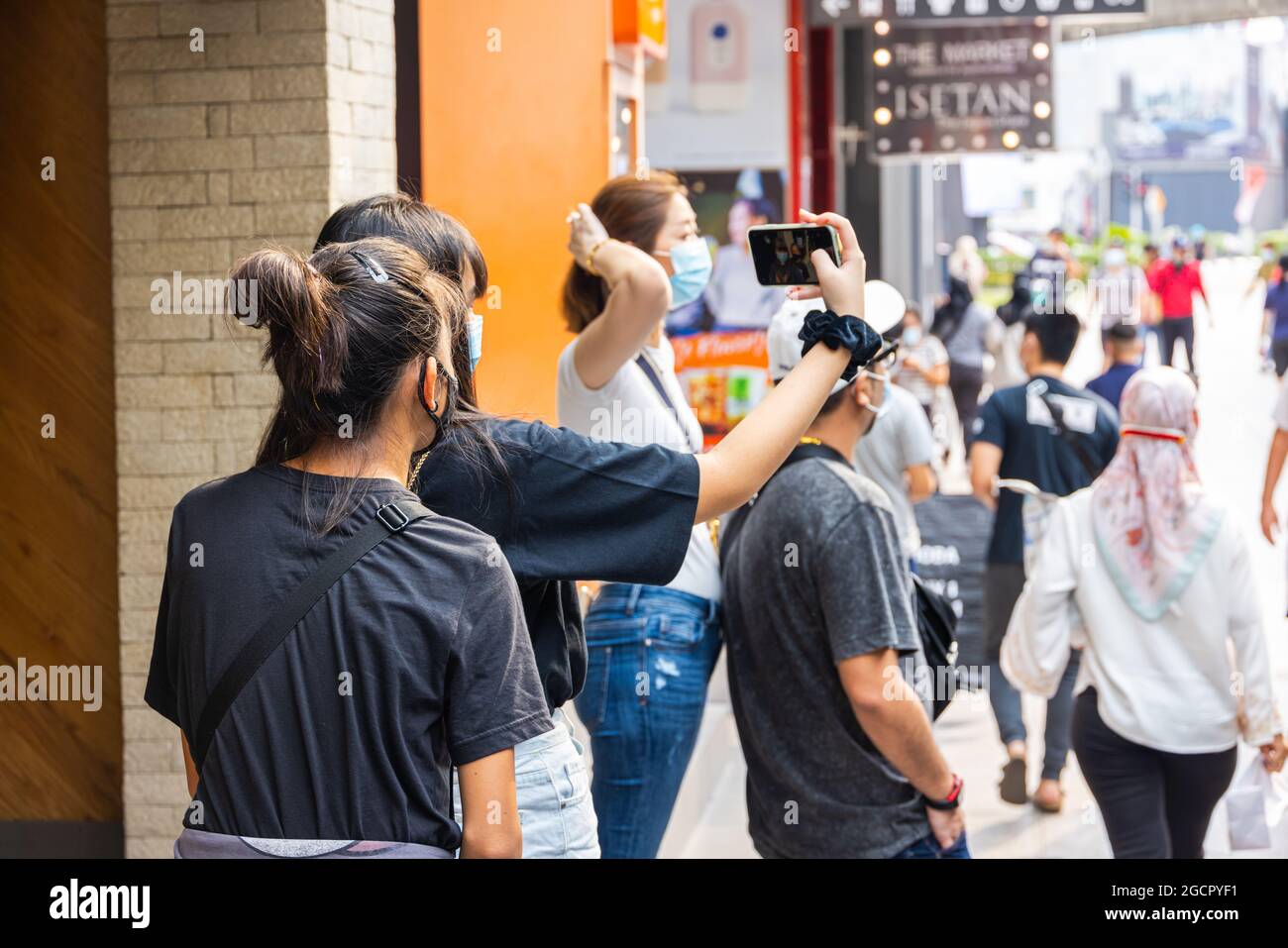 Kuala Lumpur, Malaisie - 04 octobre 2020 : deux jeunes filles asiatiques avec masque facial, prenant des photos avec leur téléphone portable dans les rues de Kuala Lumpur. FE Banque D'Images