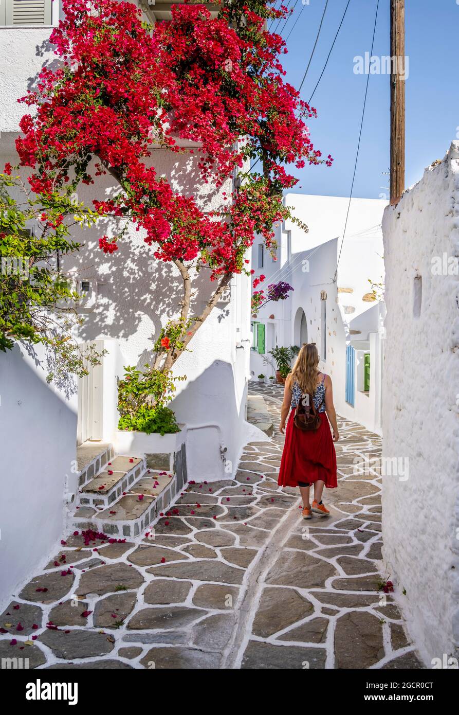 Maisons blanches et bleues avec bougainvilliers fleuris (bougainvilliers), Jeune femme avec robe rouge dans la vieille ville de Lefkes, Paros, Cyclades, Grèce Banque D'Images