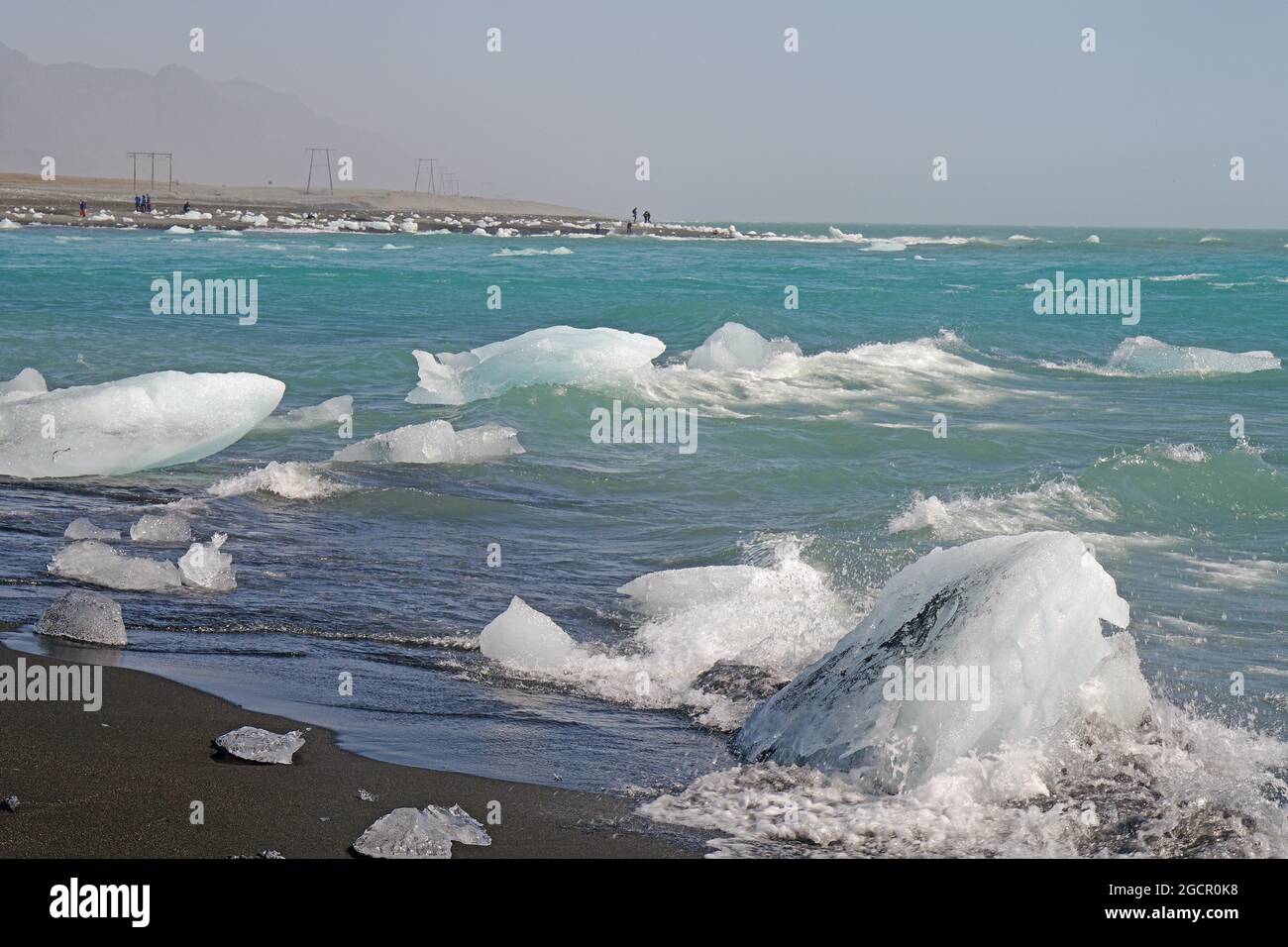 Morceau de glace sur la plage de sable noir et dans la rivière, rivière et plage en arrière-plan, Diamond Beach, Breidermerkursandur, Islande Banque D'Images