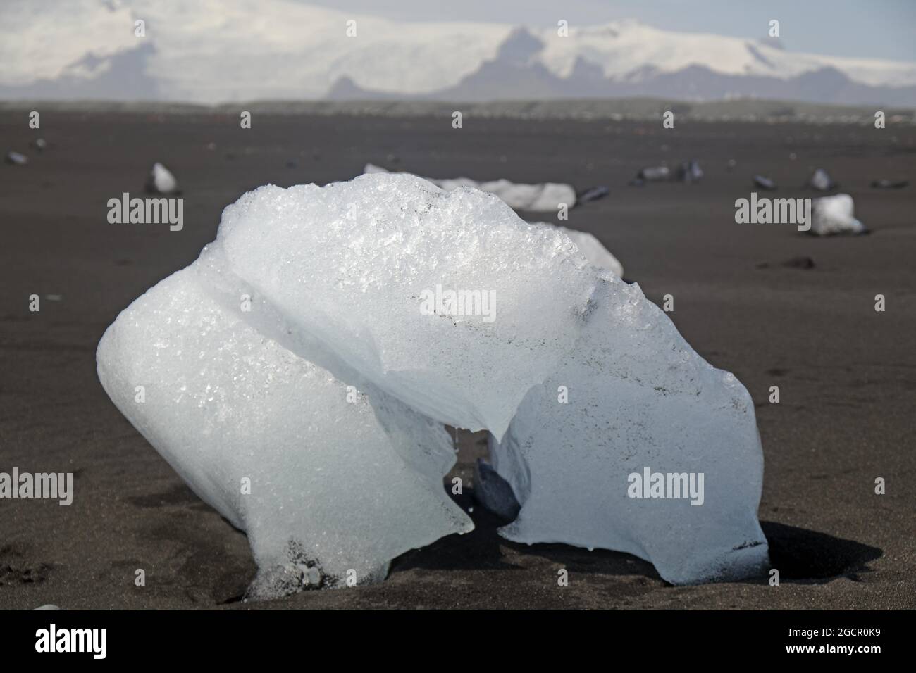 Morceau de glace sur plage de sable noir, glacier en arrière-plan, plage de diamants, Breidermerkursandur, Islande Banque D'Images