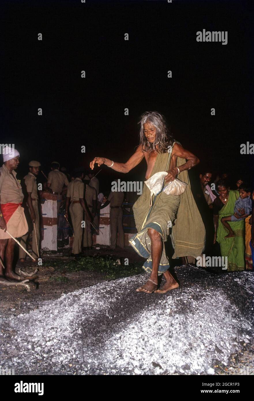 Une vieille femme qui marche sur le charbon en feu; festival de la marche au feu au Temple de Bannari Amman, Tamil Nadu, Inde Banque D'Images