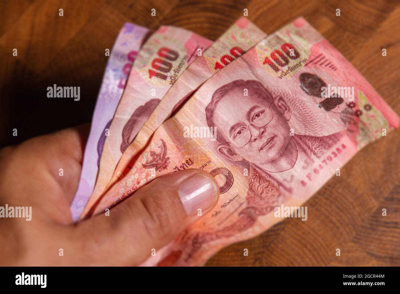 Man Hand flip thai baht banknote, la monnaie officielle de la Thaïlande. Sur le recto le portrait du Rama ou du Roi, gros plan papier argent de la Thaïlande Banque D'Images