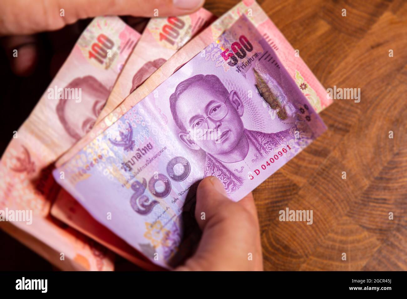 Man Hand flip thai baht banknote, la monnaie officielle de la Thaïlande. Sur le recto le portrait du Rama ou du Roi, gros plan papier argent de la Thaïlande Banque D'Images