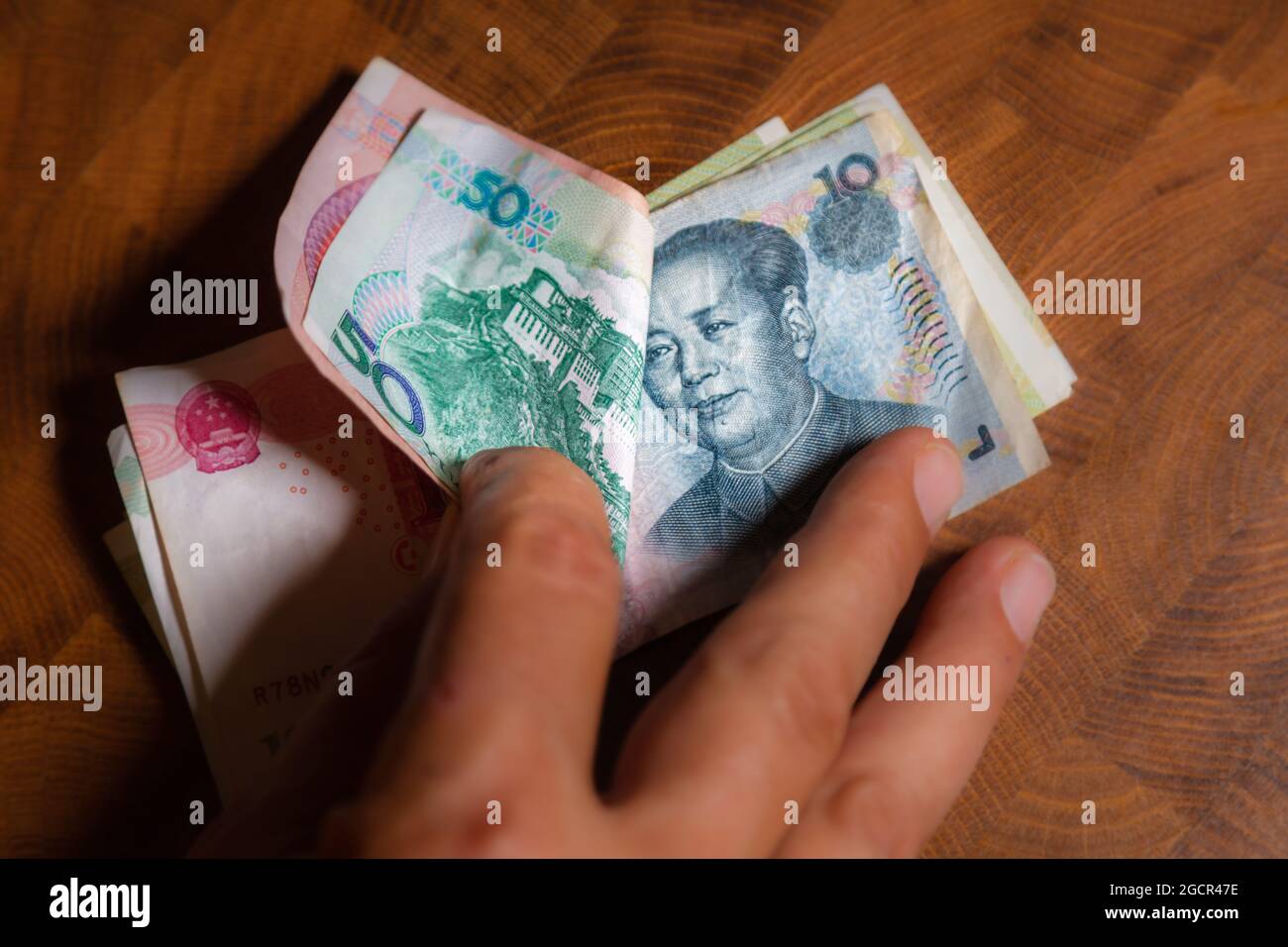 La main masculine montre le renminbi ou le yuan chinois ou le billet de banque en RMB abrégé, la monnaie officielle de la république populaire de chine. Sur l'avant du portr Banque D'Images