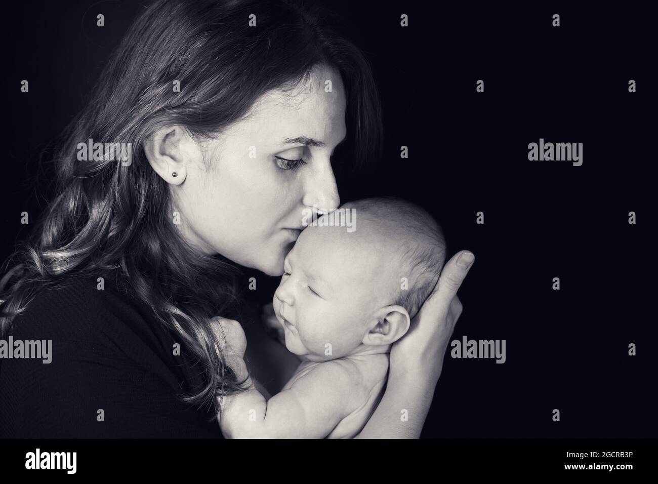 Femme Heureuse Mere Embrassant Un Nouveau Ne Garcon Dans Ses Bras Fond Noir Studio Maman Avec Un Enfant Dans Ses Mains Photo Stock Alamy