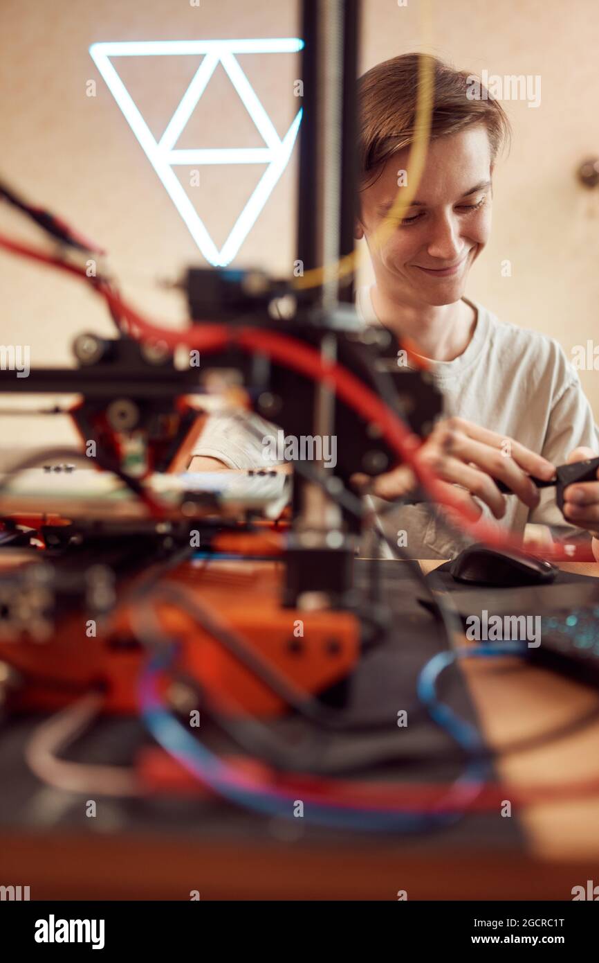 Commandes de réglage mâles anonymes à angle élevé sur l'imprimante 3D lors de la création d'un modèle en plastique dans un atelier Banque D'Images