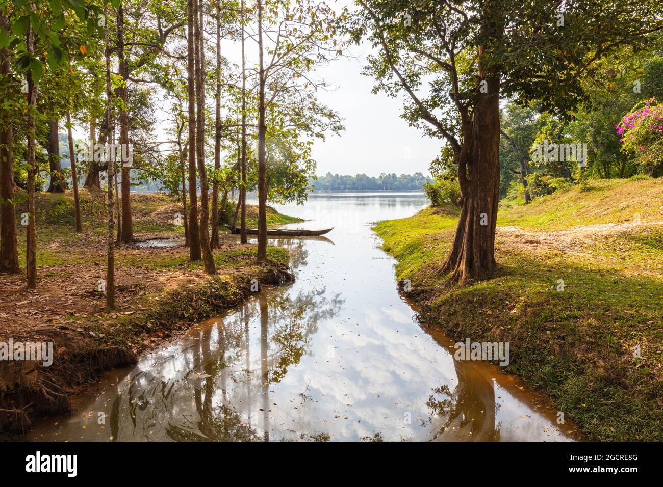 Bateau traditionnel à longue queue en bois dans un petit lac près de Siem Reap, Cambodge. Le ciel et les arbres autour se réfléchit dans l'eau. Un endroit idyllique Banque D'Images