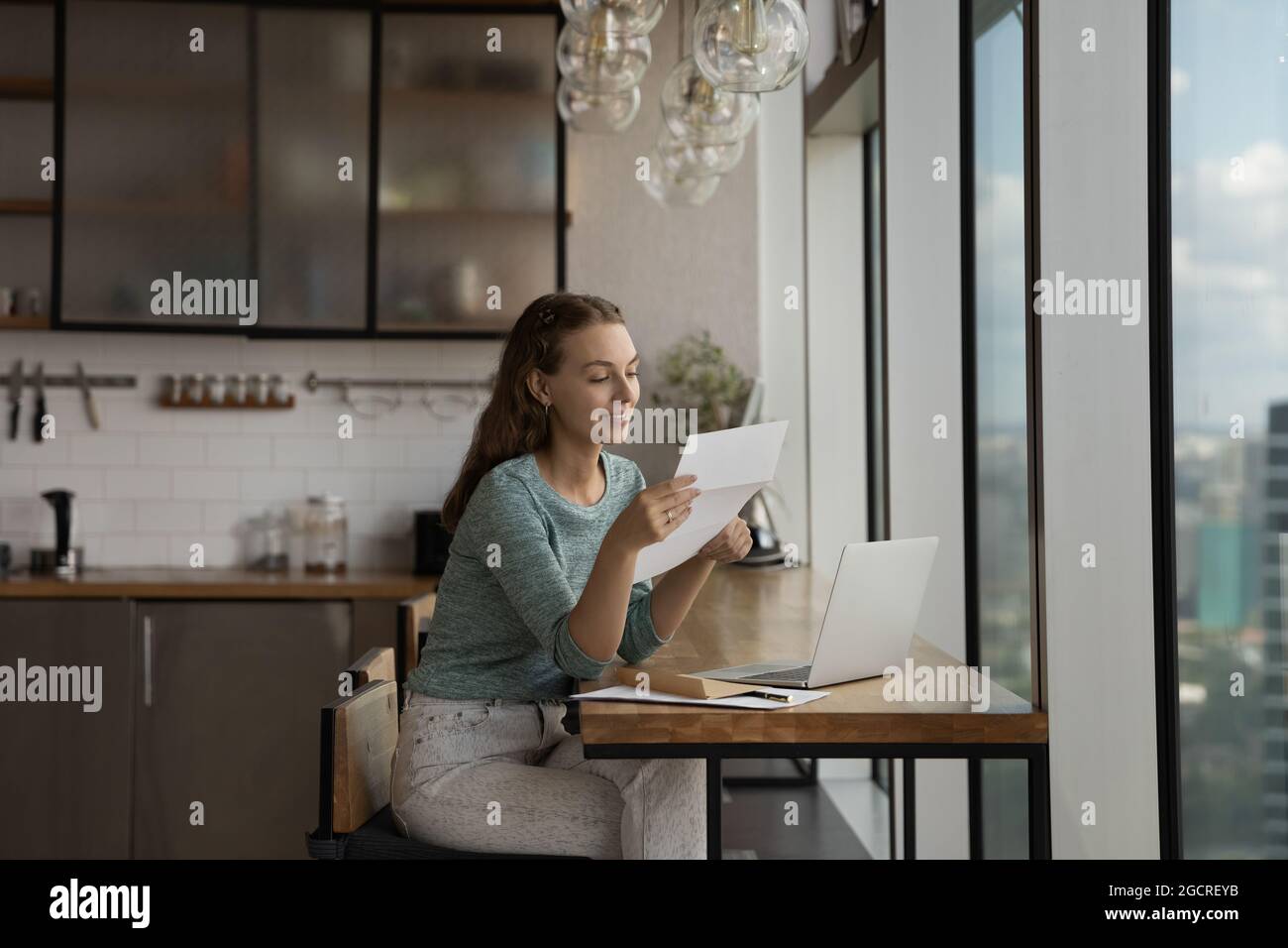 Une jeune femme heureuse lisant une lettre en papier sur son lieu de travail à domicile Banque D'Images