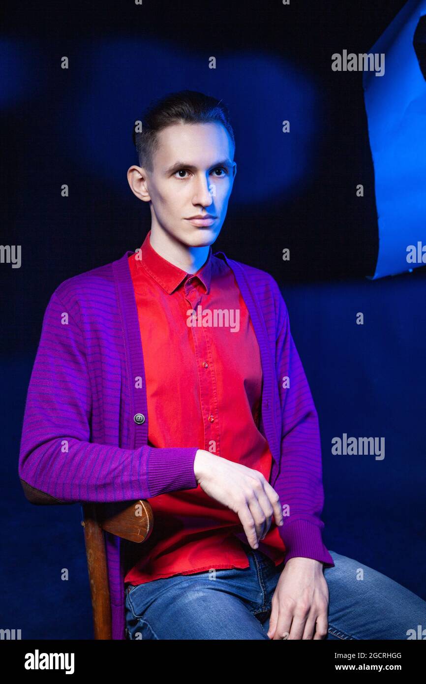 Homme élégant en chemise rouge dans un studio sombre Banque D'Images