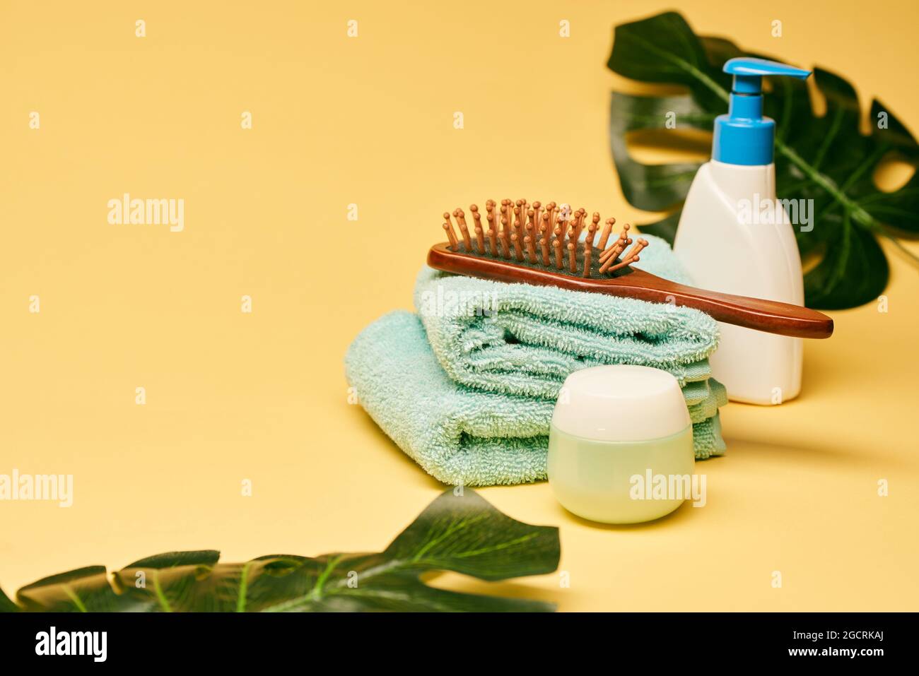 Accessoires de bain et de spa. Lotion, savon liquide, serviettes et brosse à cheveux sur fond jaune Banque D'Images