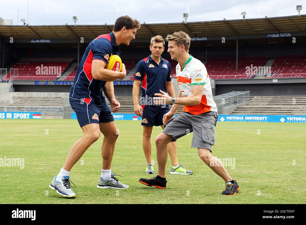 Nico Hulkenberg (GER) Sahara Force India F1 pratique ses compétences aux règles australiennes sur Wwill Minson (AUS) Western Bulldogs Australian Rules footballeur (à gauche) et Shaun Higgins (AUS) Western Bulldogs Australian Rules footballeur (au centre) de Whitten Oval. Grand Prix d'Australie, mardi 11 mars 2014. Albert Park, Melbourne, Australie. Banque D'Images