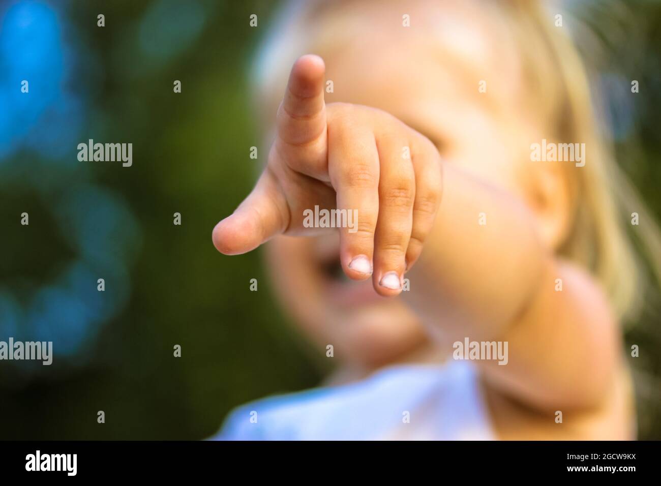Une Petite Fille Blonde De Bebe Pointant Le Doigt Sur Une Distance En Ligne Droite La Main De Bebe Fille Au Foyer 2 3 Ans Jeunes Enfants Dans Un Ap Vert Photo Stock