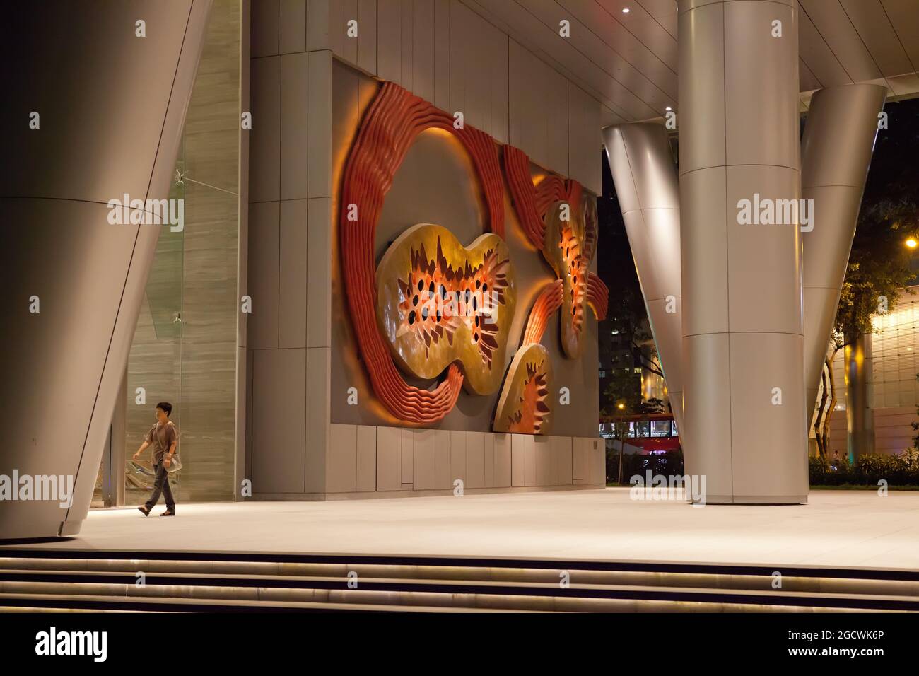 Une figure solitaire passe devant une œuvre d'art publique à Singapour Banque D'Images