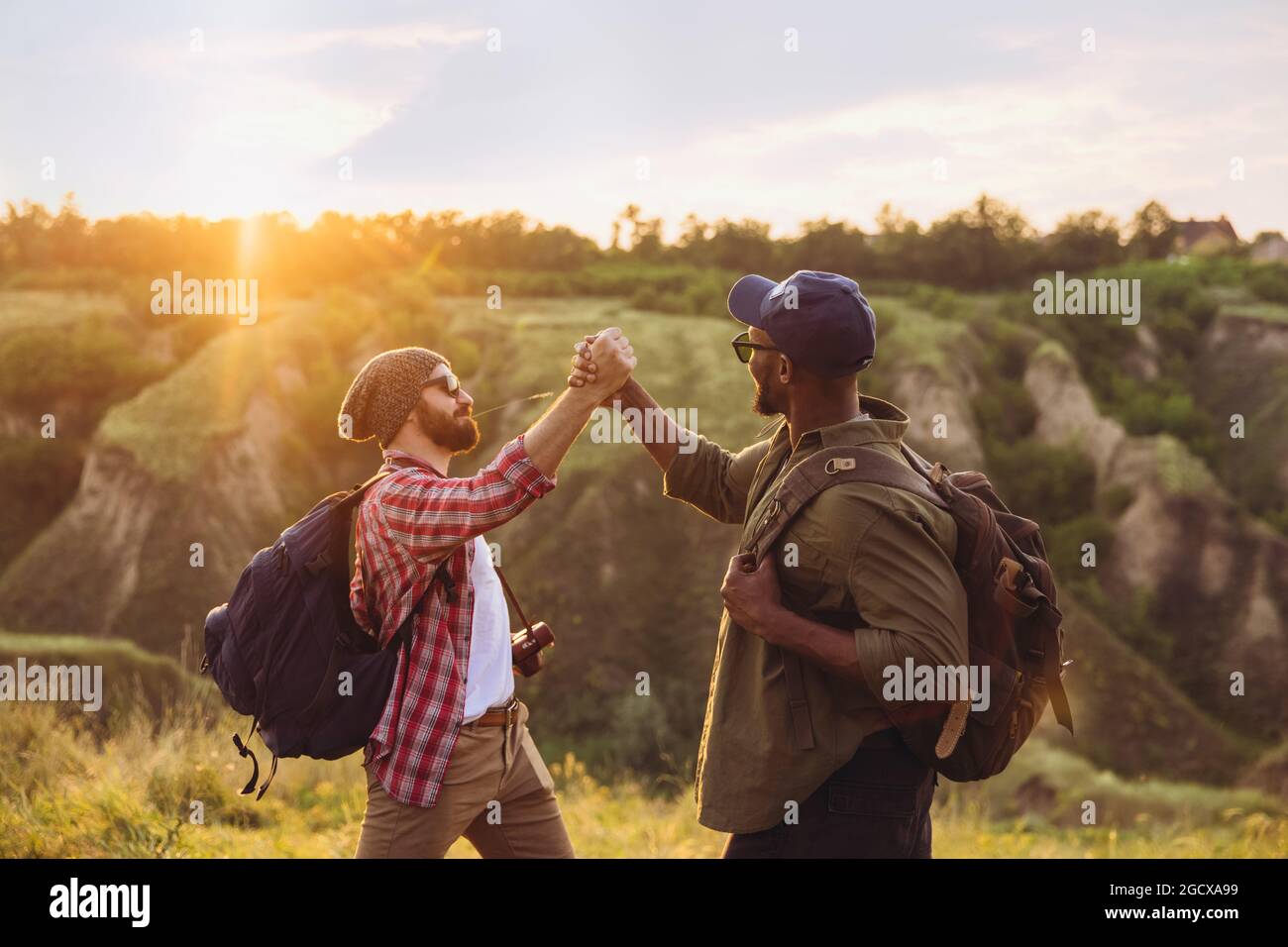 Jeunes hommes, amis marchant, se promenant dans les environs de la ville, en forêt d'été. Mode de vie actif, voyage, concept de soutien Banque D'Images