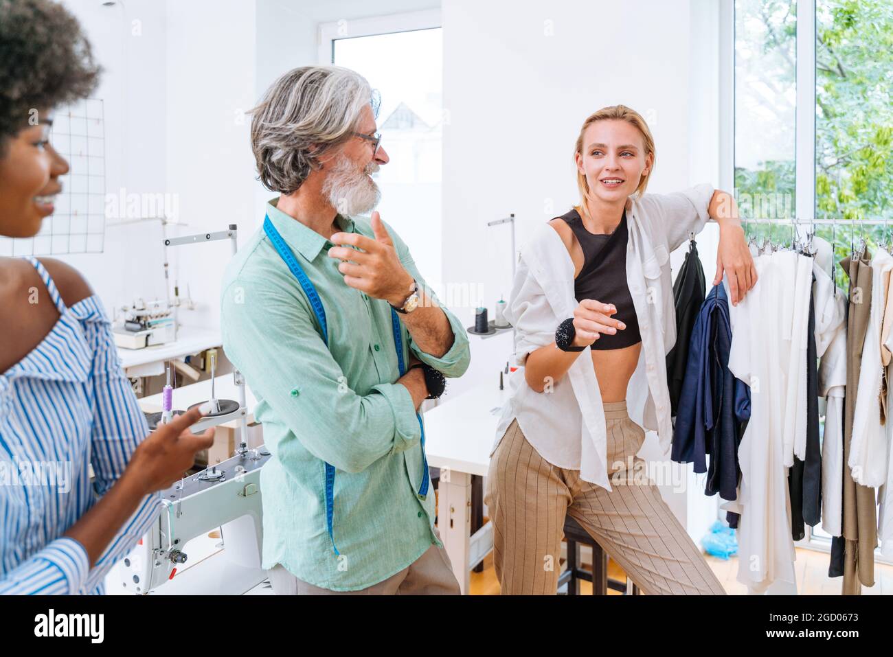 Équipe multiethnique de créateurs de mode travaillant dans un atelier de démarrage de vêtements - groupe multiracial de stylistes, de designers sur mesure et de couturiers travaillant dans Banque D'Images