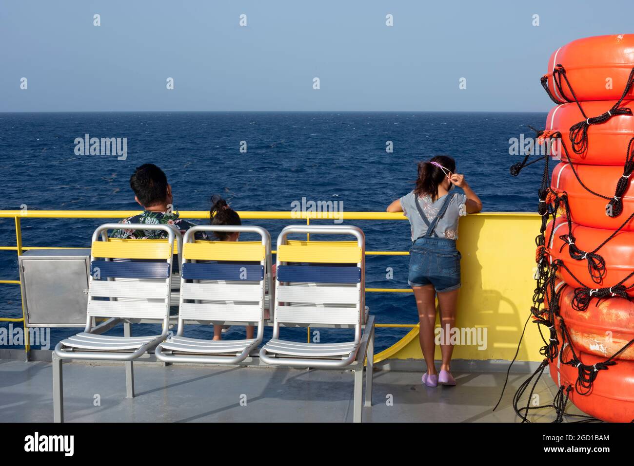 Trois passagers assis sur un ferry en mer qui regarde l'horizon au-dessus de la mer des Caraïbes près de la côte mexicaine. Banque D'Images